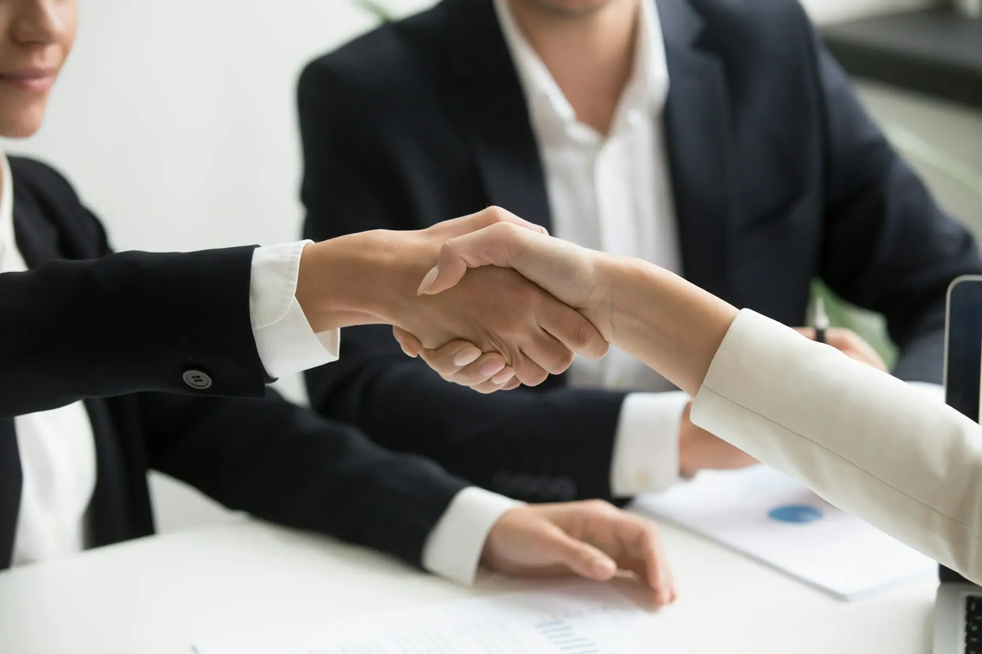 Business partners shaking hands across a meeting table